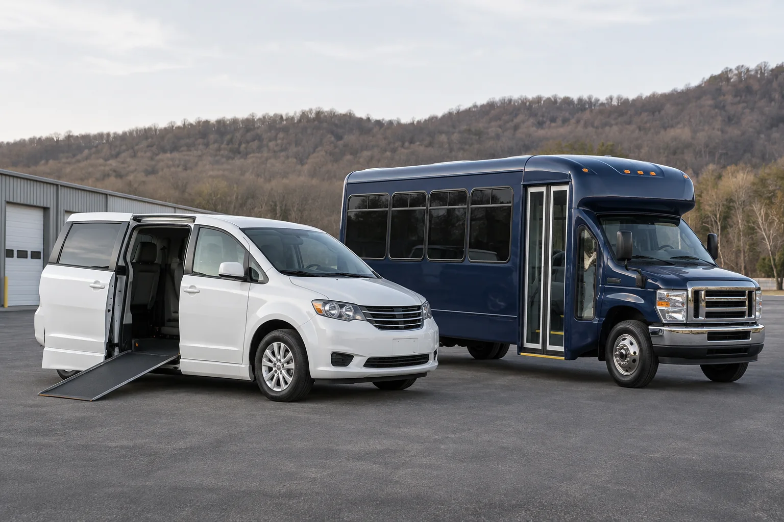 White wheelchair van and navy shuttle at regional depot against distant neutral wooded hills.